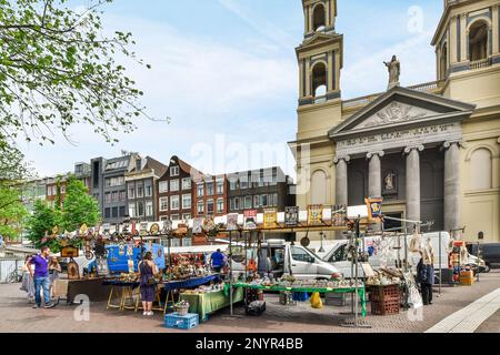 Ein Außenmarktbereich mit Leuten, die auf dem Gehweg vor einem großen Kirchensteil einkaufen und Artikel verkaufen Stockfoto