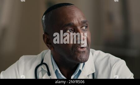 Verwirrter, durchdachter Senior männlicher professioneller Arzt reifer Erwachsener Arzt afroamerikanischer Mann in der medizinischen Kittelplanung Idee Brainstorming Denken Stockfoto