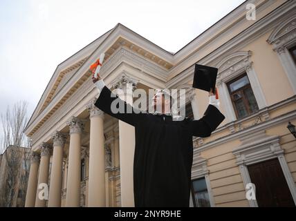 Glücklicher Student mit Abschluss nach der Abschlussfeier im Freien, Blick aus dem niedrigen Winkel Stockfoto