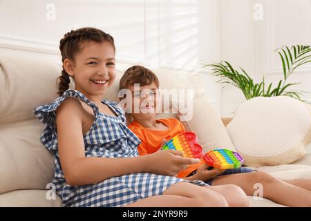 Kinder, die zu Hause mit Pop-IT-Spielzeugen spielen, werden zu Hause auf dem Sofa fündig Stockfoto