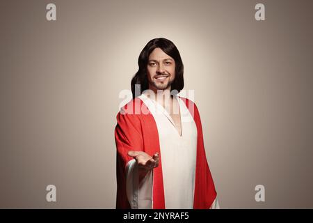 Jesus Christus streckt seine Hand auf beigefarbenem Hintergrund aus Stockfoto