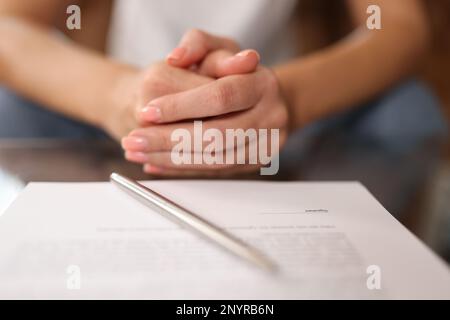 Frau sitzt am Tisch, Dokumente zur Unterschrift Stockfoto