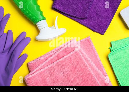Mikrofasertücher und Reinigungsmittel auf gelbem Hintergrund, flach verlegt Stockfoto