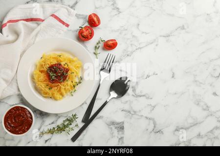 Leckerer Spaghetti-Kürbis mit Thymian und Tomatensoße, serviert auf einem weißen Marmortisch, flach liegend. Platz für Text Stockfoto