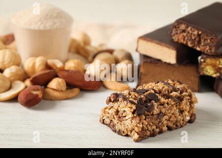 Verschiedene leckere Proteinriegel und Nüsse auf dem weißen Tisch, Nahaufnahme Stockfoto