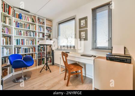 Amsterdam, Niederlande - 10. April 2021: Ein Raum mit Schreibtisch, Stuhl und Bücherschalen an der Wand dahinter ist ein Bücherregal voller Bücher Stockfoto