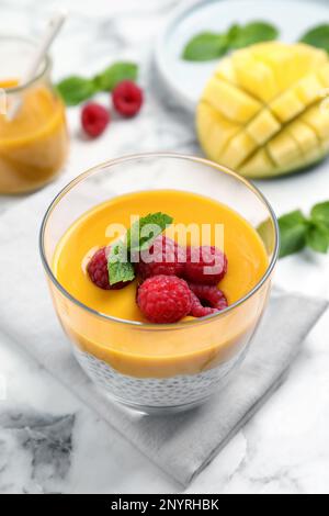 Köstlicher Chia-Pudding mit Mangosauce und Himbeeren auf einem weißen Marmortisch Stockfoto