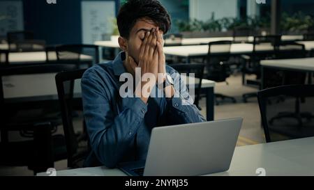 indisch-arabischer multiethnischer Geschäftsmann krank müde erschöpfter 30s Manager Mitarbeiter tippt auf Laptop Verlust Business Projekt Problem mit Computer Stockfoto