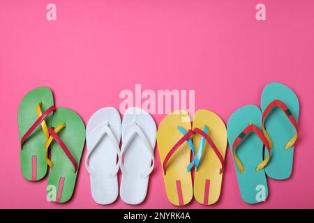 Viele verschiedene Flip-Flops auf pinkfarbenem Hintergrund, flach liegend. Platz für Text Stockfoto