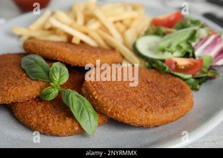 Köstliche gebratene panierte Schnitzel mit Garnierung auf dem Tisch, Nahaufnahme Stockfoto