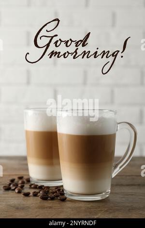 Heißer Kaffee mit Milch in Glasbechern und Bohnen auf einem Holztisch. Guten Morgen Stockfoto