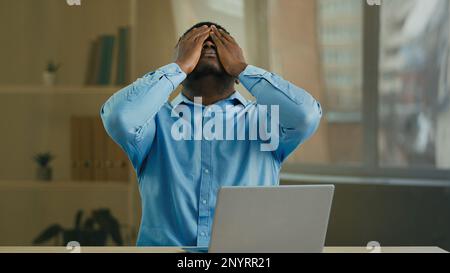 Verzweifelter, trauriger wütender afroamerikanischer Geschäftsmann Manager Unternehmer, der mit einem Laptop im Büro arbeitet, hat Computerproblem kaputtes Gerät falsch gesendet Stockfoto