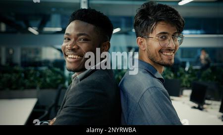Geschäftskollegen verschiedene ethnische Männer, afrikanischer Mann und indischer männlicher Geschäftsmann erfolgreiche Büroangestellte, die lächelnd dastehen Stockfoto
