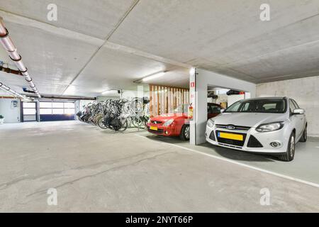 Amsterdam, Niederlande - 10. April 2021: Ein Auto parkt in einem Parkhaus mit Fahrrädern auf dem Regal und Fahrradträgern an der Wand dahinter Stockfoto