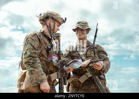 USA Marinekorps 1. LT. Sean Conner, Left, und 1. LT. Thomas Cunningham, beide Platoonkommandanten mit Bataillon Landing Team 1/4, 31. Marine Expeditionary Unit, überprüfen ihre Positionen während einer Razzia auf Kin Blue Beach, Okinawa, Japan, 7. Februar 2023. Die Razzia erhöhte die Fähigkeiten der Marines, umkämpfte Gebiete zu sichern und freundlichen Truppen zu ermöglichen, von Schiff zu Küste voranzukommen. Die MEU 31. operiert an Bord von Schiffen der America Amphibious Ready Group im Flottenbereich 7., um die Interoperabilität mit Verbündeten und Partnern zu verbessern und als einsatzbereite Eingreiftruppe zu fungieren Stockfoto
