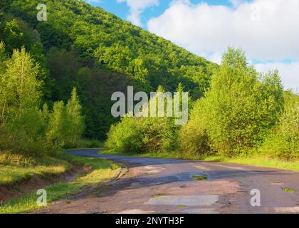 Die Straße führt durch die friedliche Landschaft und bietet Reisenden einen malerischen Pfad. Die ruhige Landschaft wird nur durch die majestätischen Berge auf t unterbrochen Stockfoto