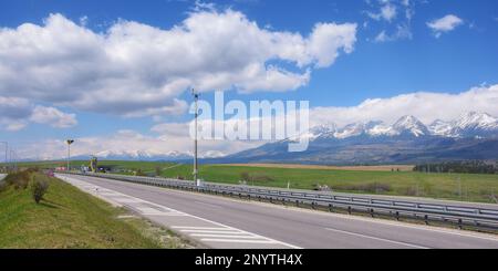 fahren sie durch die slowakische Landschaft und genießen Sie einen malerischen Blick auf die wunderschöne tatra. Die Straße führt durch ein riesiges Ackerland und bietet eine Stockfoto