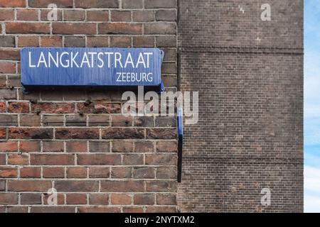 Amsterdam, Niederlande - 10. April 2021: Straßenschild an der Seite eines Ziegelgebäudes mit blauem Himmel im Hintergrund und einigen weißen Wolken Stockfoto