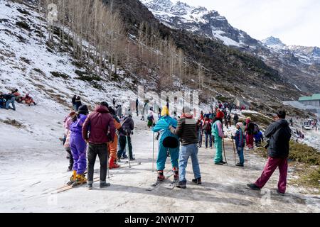 Panning-Aufnahme von Menschen in Winterkleidung, die im Schnee spielen, Ski fahren, rutschen, am Snow Point in Lahul, manali solang ein beliebter Touristenort während Stockfoto