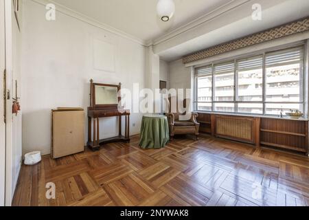 Wohnzimmer im Vintage-Stil mit wunderschönen Hartholzböden, losen Möbeln und einem großen Aluminium- und Glasfenster Stockfoto