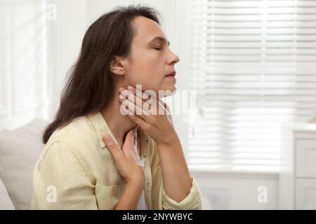 Reife Frau, die zu Hause eine Schilddrüsen-Selbstuntersuchung macht. Platz für Text Stockfoto