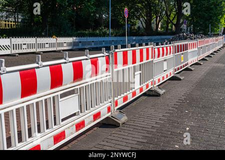 Auf dem Fußgängerbelag der Straße steht eine große Gruppe von weißen und roten Kunststoffbarrieren. Reparaturarbeiten. Stockfoto