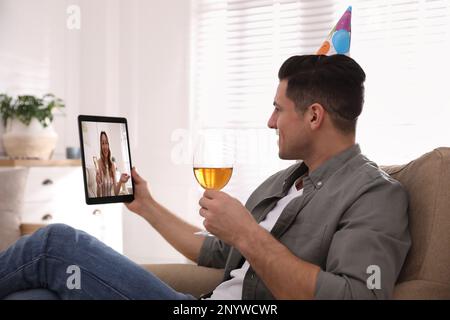 Mann mit einem Glas Wein hat online Party über Tablet zu Hause während Quarantäne Abriegelung Stockfoto