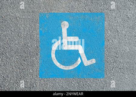 Rollstuhl-Symbol auf Asphaltstraße, Draufsicht. Behindertenparkschein Stockfoto