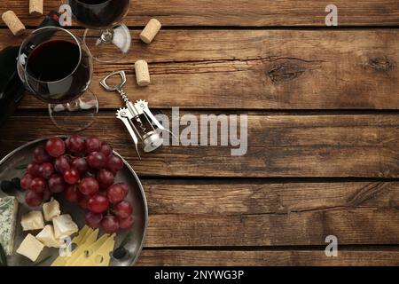 Leckerer Rotwein und Snacks auf Holztisch, flach liegend. Platz für Text Stockfoto