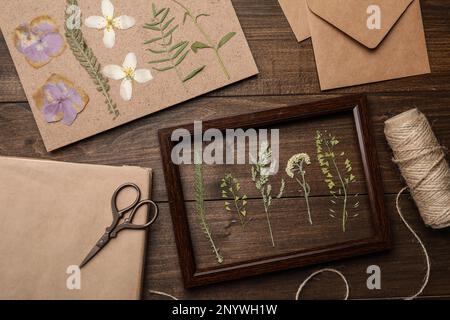 Flache Laienzusammensetzung mit getrockneten Blumen und Pflanzen auf Holztisch Stockfoto