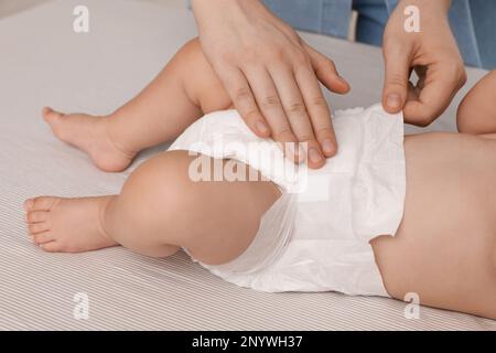 Mutter, die die Windel des Babys wechselt, auf dem Bett, schließen Stockfoto