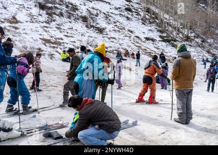 Panning-Aufnahme von Menschen in Winterkleidung, die im Schnee spielen, Ski fahren, rutschen, am Snow Point in Lahul, manali solang ein beliebter Touristenort während Stockfoto