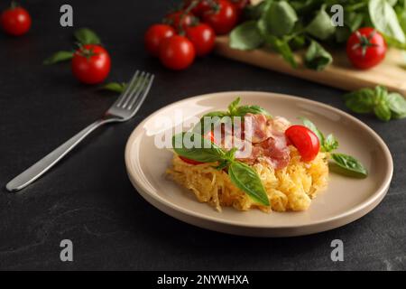 Schmackhafter Spaghetti-Kürbis mit Speck und Basilikum, serviert auf einem schwarzen Tisch Stockfoto