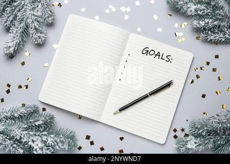 Wortziele in Notizbuch und Weihnachtsdekor auf hellgrauem Hintergrund, flach liegend Stockfoto
