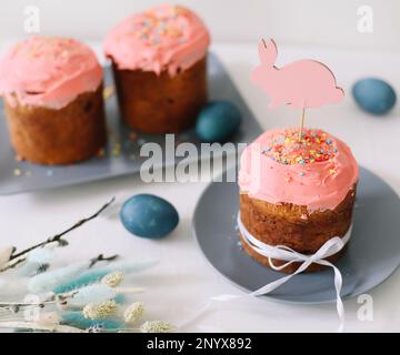 Leckerer Osterkuchen, bemalte Eier, Weidenzweige und Spielzeughase auf dem Tisch Stockfoto