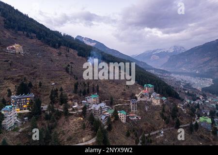 Drohnenlandung aus der Luft mit beleuchteten mehrstöckigen Gebäuden am Abend auf der Seite des Hügels, wobei die Einkaufsviertel der Hotels in manali, shimla, gezeigt werden Stockfoto