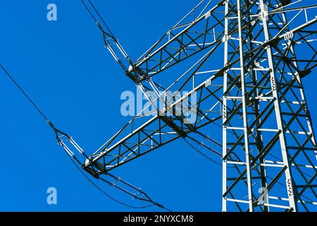 Fragment eines Hochspannungsmastes mit gedehnten Drähten gegen den blauen Himmel. Stockfoto