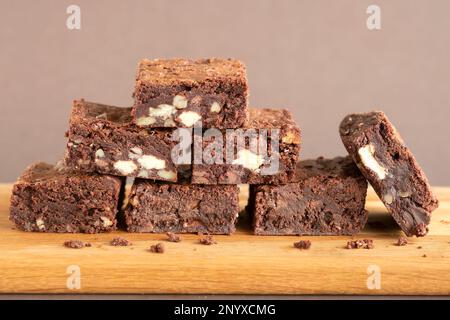 Eine Charge frisch gebackener dreifach-Schokoladen-Brownies auf einer Holzplatte. Die Brownies sind noch warm und klebrig. Ein Genuss Stockfoto