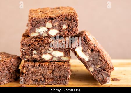 Eine Charge frisch gebackener dreifach-Schokoladen-Brownies auf einer Holzplatte. Die Brownies sind noch warm und klebrig. Ein Genuss Stockfoto