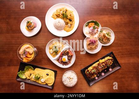 Set aus typischen peruanischen Gerichten mit bekannten Rezepten, Ceviches, Lomo-Saltado, Huancaina-Kartoffeln auf Holztisch Stockfoto