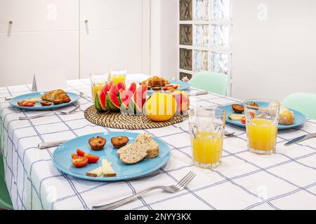 Ferienwohnung Apartment mit Esstisch mit Tischdecke und Frühstück serviert mit viel Obst und ein paar Süßigkeiten Stockfoto