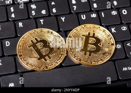 Zwei alte, staubige Goldmünzen, Münzsymbole auf einer alten Laptop-Computer-Tastatur, Objekt-Nahaufnahme, niemand, keine Menschen. Krypto-Währungskrise, C. Stockfoto