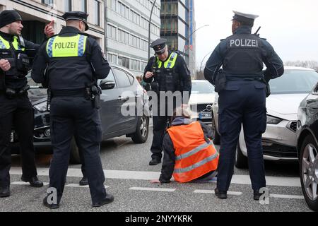 Hamburg, Deutschland. 02. März 2023. Aktivisten der Umweltgruppe "Last Generation", die sich auf der Glockengießermauer in der Nähe des Hauptbahnhofs niedergelassen haben, sind von Polizisten umgeben. Sie wollen die Aufmerksamkeit auf die Einhaltung der Klimaziele lenken. Kredit: Bodo Marks/dpa/Alamy Live News Stockfoto