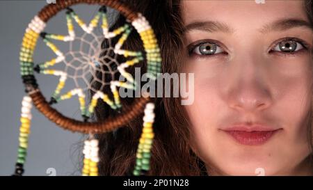 Das junge Mädchen hält ein Foto von einem mystischen Traumfänger Stockfoto