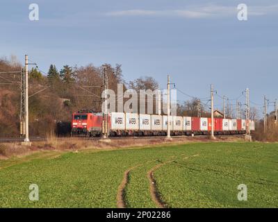 Leitmeritz, Tschechische Republik - 03. März 2021: Elektrischer Güterzug der Deutschen Bahn mit Güterwagen, die MAERSK-Container halten, Landwirtschaftsfeld, sonnig Stockfoto