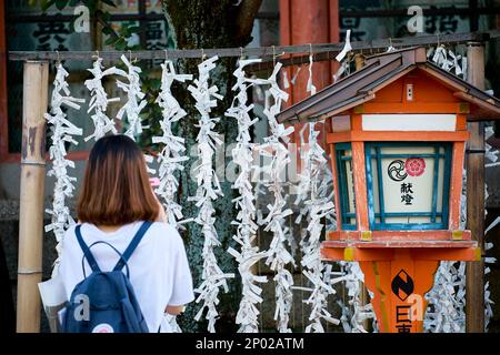 Frau steht vor Omikuji (Fortune Papers) am Yasaka-Schrein, Kyoto, Japan Stockfoto