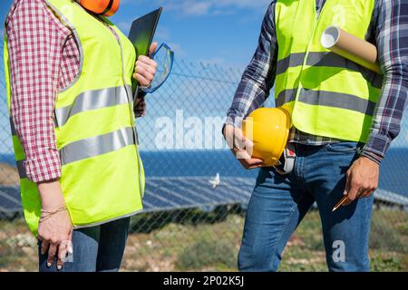 Nahaufnahme der Körper zweier Ingenieure mit reflektierender Weste und Werkzeugen Stockfoto