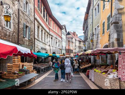 Annecy, Frankreich - 7. Januar 2022: Menschen, die Gemüse und Obst auf dem Markt in der mittelalterlichen historischen Altstadt von french Annecy mit farbenfroher Umgebung kaufen Stockfoto