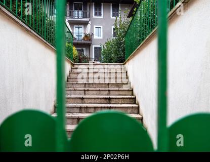 Blick durch den grünen Zaun in Richtung der Treppe zum Haus Stockfoto