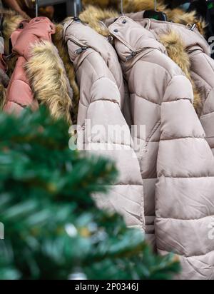Wintermäntel an Kleiderbügeln vor dem Geschäft während des Weihnachtsangebots Stockfoto